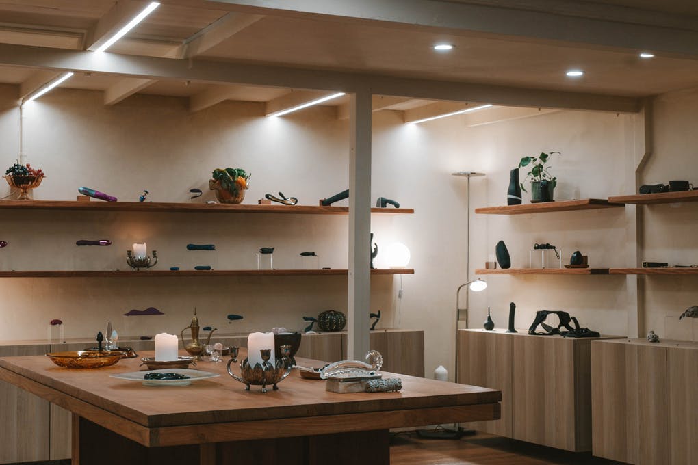 A dim lit shop with wood shelving and sex toys.